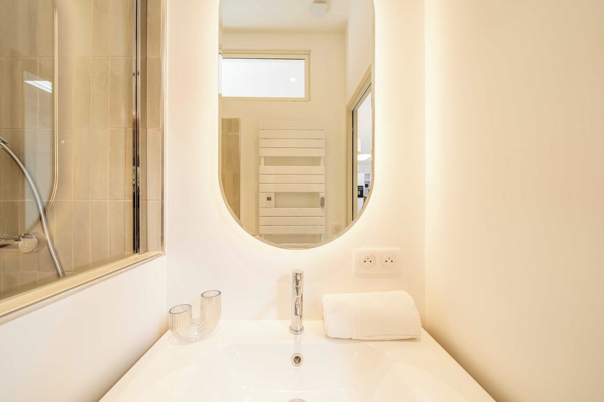 A bathroom with a white sink, a mirror, a towel, and a shower.