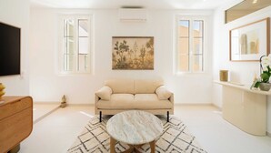 A modern living room with a beige sofa, a round coffee table, and a painting on the wall.