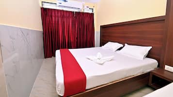 A hotel room with a bed, a wooden headboard, a red curtain, and a marble floor.