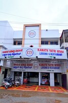 Un edificio de varios pisos con señalización que indica 'KYN' y 'KAMATH YATRI NIVAS LODGING & RESTAURANT'.