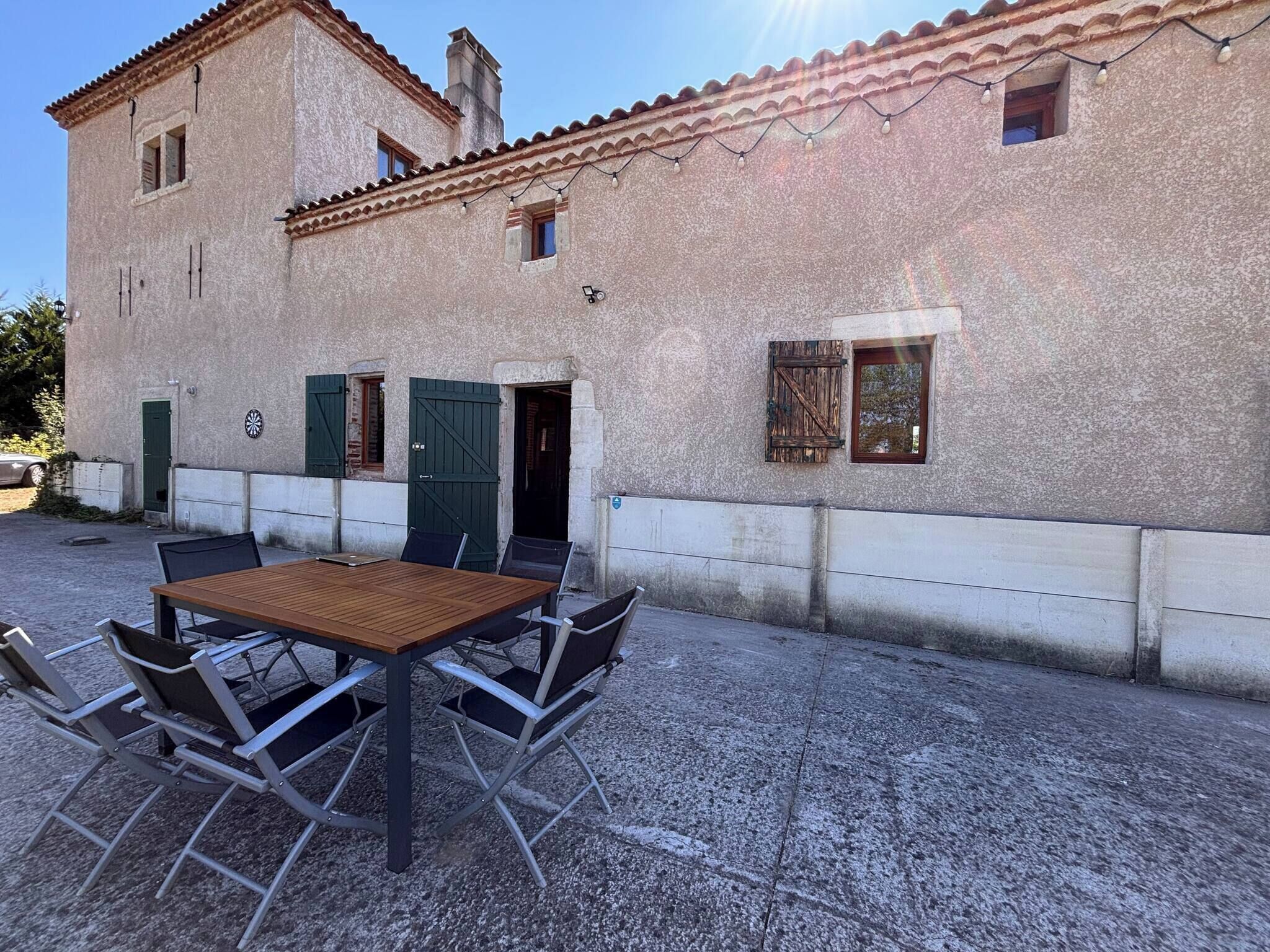 Un edificio con un patio attrezzato con tavolo e sedie.
