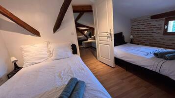Una camera da letto con due letti, soffitto in legno, parete in mattoni e una finestra.