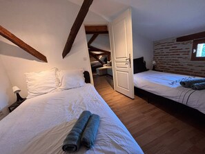 Una camera da letto con due letti, soffitto in legno, parete in mattoni e una finestra.