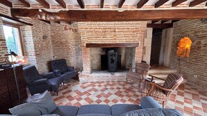 A room with a fireplace, a sofa, and a chair. - Une Belle Histoire holiday home (Sainte-Livrade-sur-Lot)