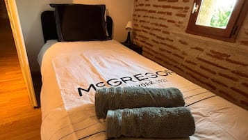 Quarto de hotel com cama, mesa de cabeceira, abajur, janela com vista e porta.