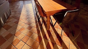 A dining area with a large wooden table and chairs, a tiled floor, and a view through a glass door. - Une Belle Histoire holiday home (Sainte-Livrade-sur-Lot)