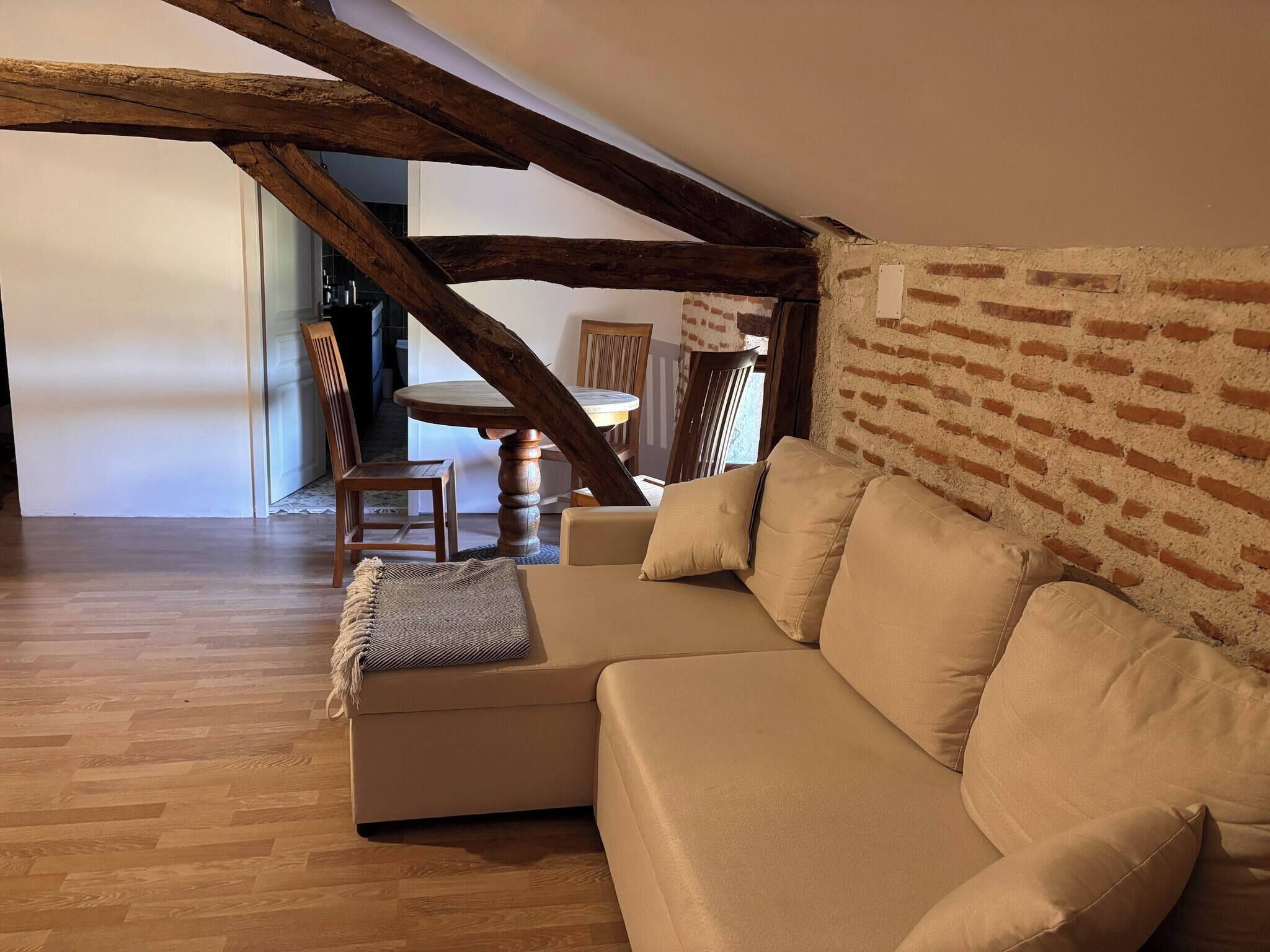En hyggelig stue med en beige sofa, træbjælker og en murstensvæg.