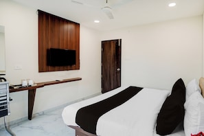 A hotel room with a bed, a desk with a flat-screen TV, a wardrobe, and a ceiling fan. - Super Collection O Omkar Nagar Nagpur (Nagpur)