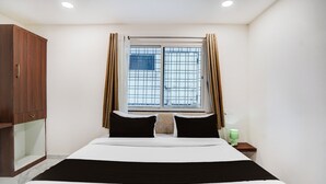Quarto com cama, guarda-roupa, janela com cortinas e mesa de cabeceira com abajur.