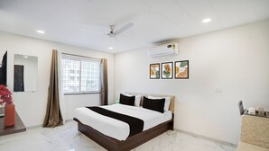 Quarto de hotel com cama, janela com cortinas, unidade de ar condicionado e uma obra de arte na parede.