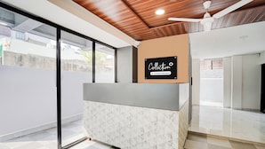 Um balcão de recepção com placa da empresa, um ventilador de teto e piso xadrez.