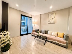 A modern living room with a sofa, coffee table, and a large window. - Sea View 2 Bed Room Best Location (Muang Pattaya)
