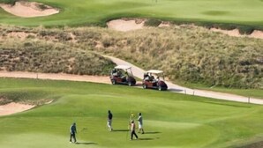 En golfbana med bunkrar, en vattenyta och en väg för golfbilar.