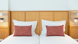 Una cama doble con dos almohadas, cabecera de madera y lámparas de noche.