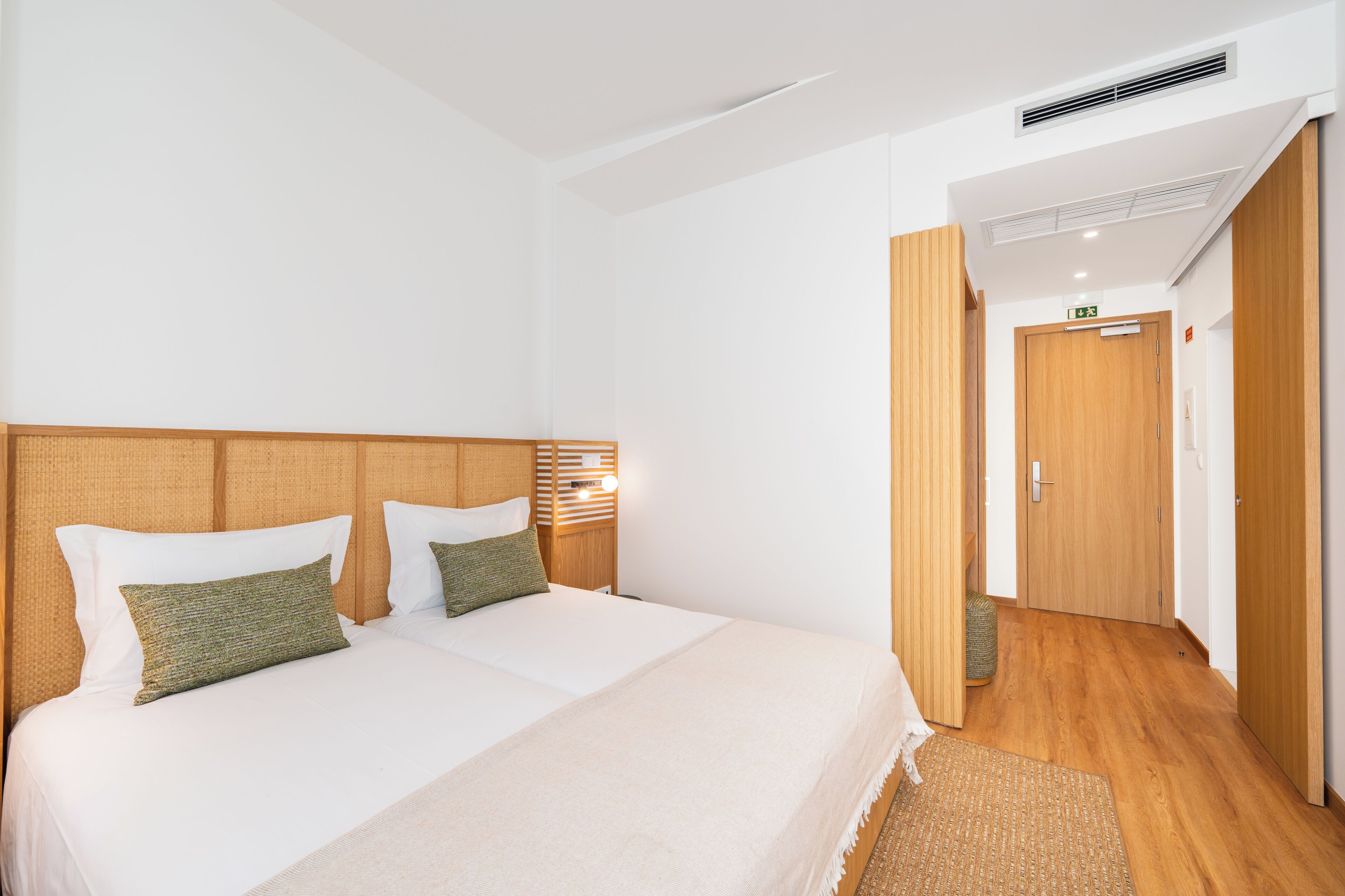 A hotel room with a large bed, a wooden headboard, a bedside table, and a nightstand.