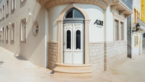A building with a prominent entrance, a sign reading 'ALLLUX,' and a stone facade.