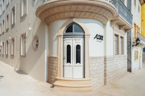 A building with a prominent entrance, a sign reading 'ALLLUX,' and a stone facade.