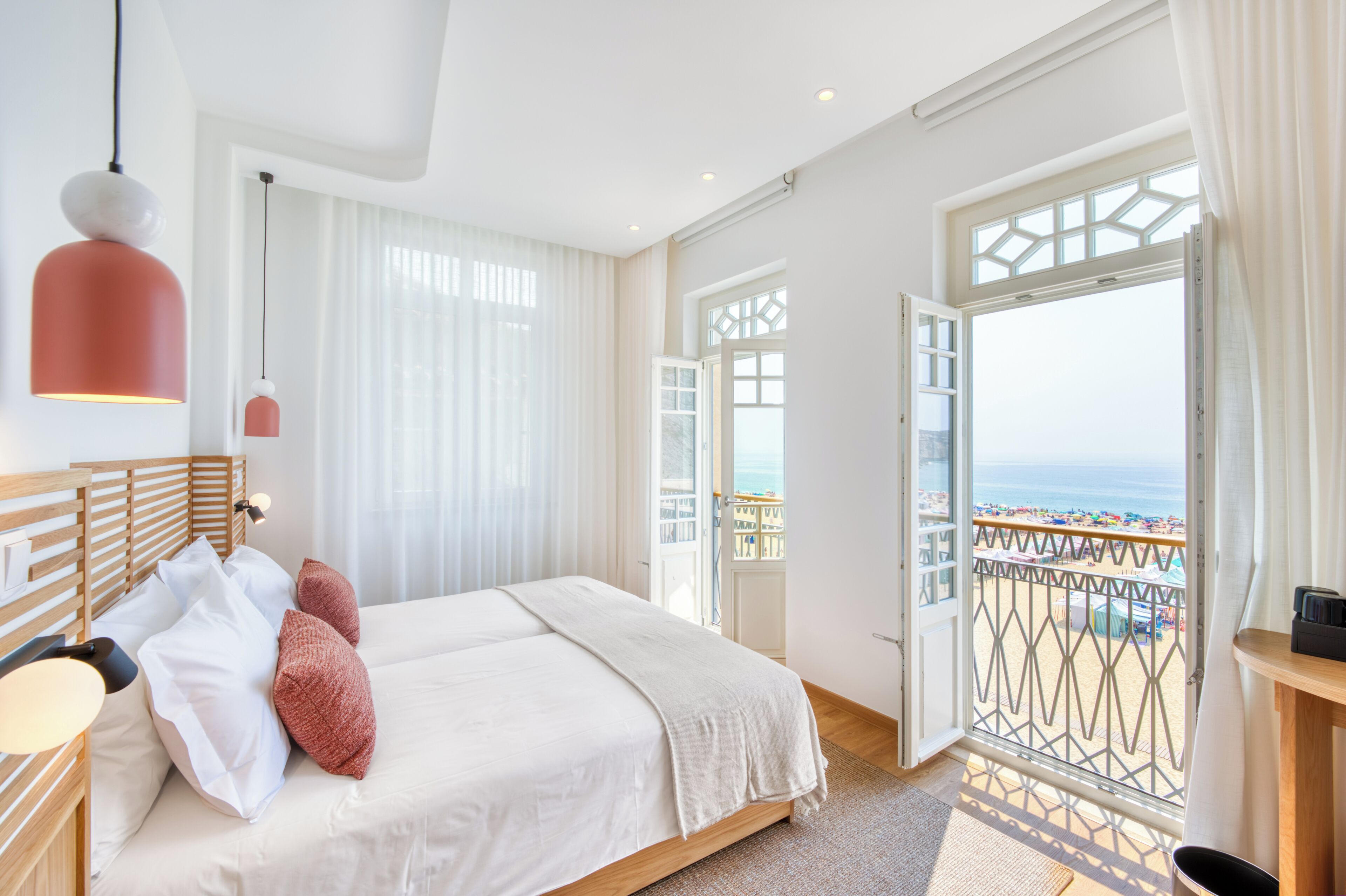 Een hotelkamer met een bed, een bureau, uitzicht op het strand en een balkon.