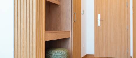 A wooden wardrobe with a handle, a shelf, and a small woven basket.