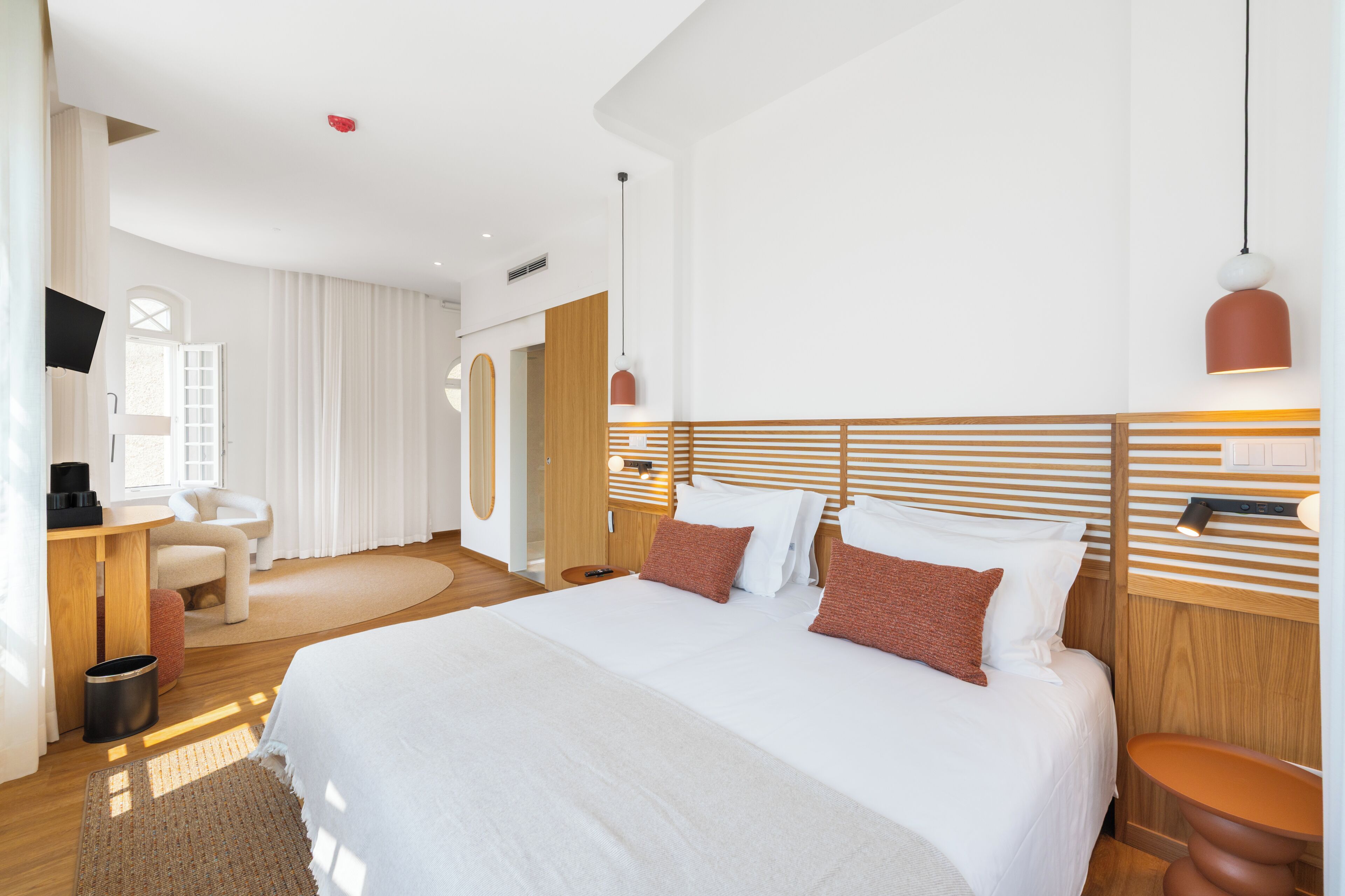 A modern hotel room with a large bed, a desk, a chair, and a television.