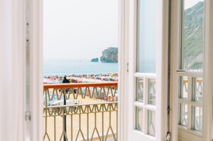 Une vue sur une plage avec des tentes et des parasols, une falaise rocheuse et la mer.