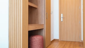 Un armario de madera con un tirador, un contenedor de almacenamiento rojo pequeño y una puerta de madera con un tirador.