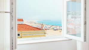 A window with a view of a beach with umbrellas and buildings.