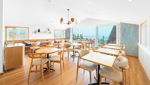 Un comedor moderno con mobiliario de madera, ventanas amplias y vista al mar.