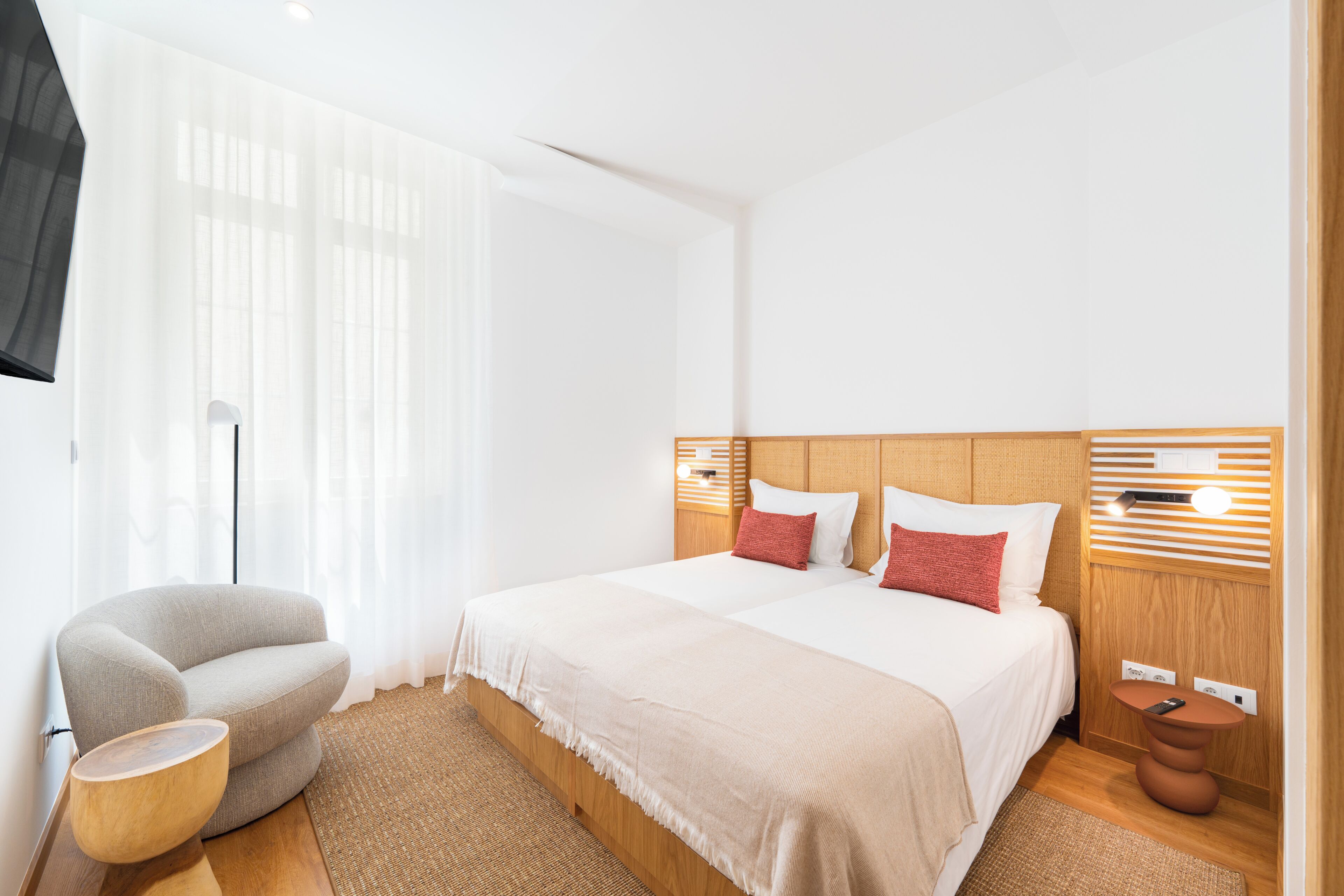 Una habitación de hotel con una cama grande, una silla, una mesita de noche y una lámpara.
