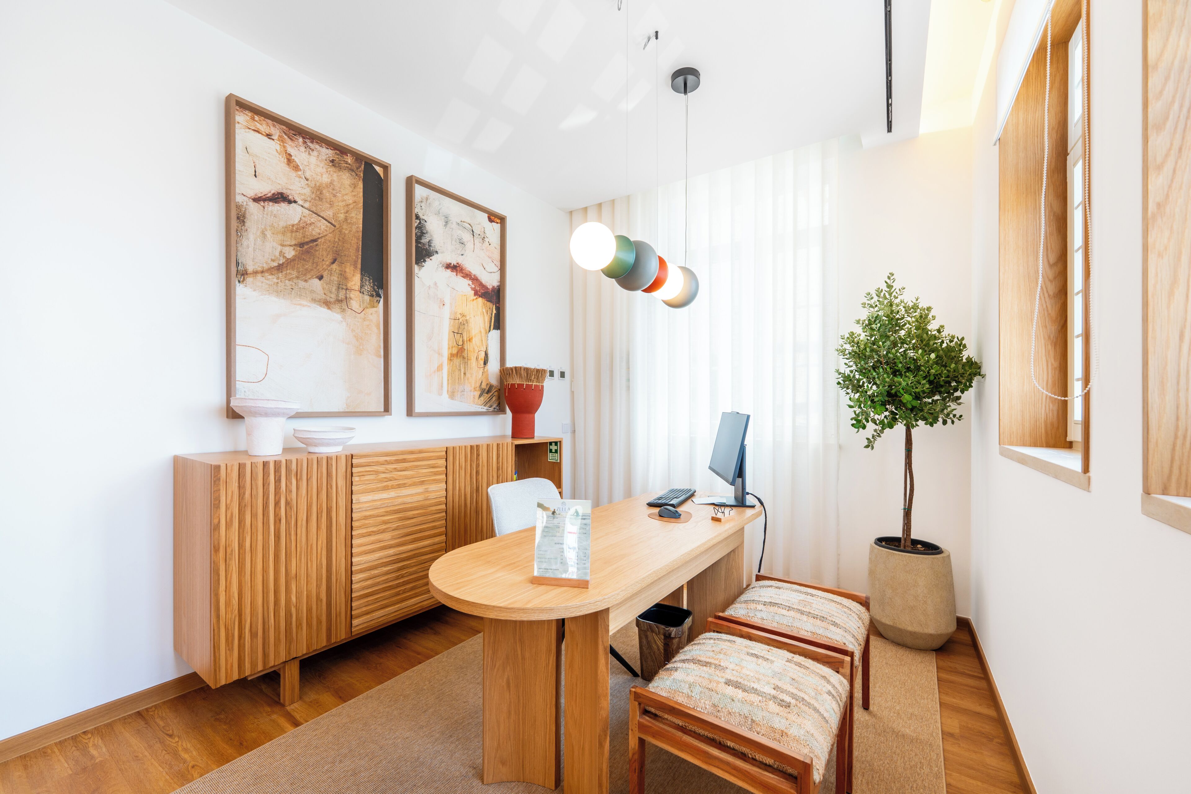 Un comedor moderno con una mesa de madera, sillas, una planta en maceta y una obra de arte abstracta en la pared.
