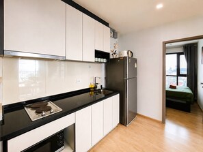 Una cocina moderna con armarios blancos, encimera negra, refrigerador de acero inoxidable y ventana con vista a la ciudad.