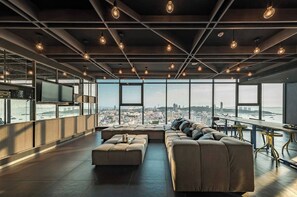 Un salón moderno con un sofá grande, un televisor de pantalla plana y vistas a la ciudad.