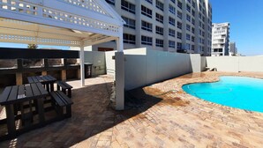 A hotel with a swimming pool, outdoor seating, and a covered patio area. - Amazing View For Less Bloubergstrand Beachfront (Cape Town)