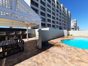 A hotel with a swimming pool, outdoor seating, and a covered patio area. - Amazing View For Less Bloubergstrand Beachfront (Cape Town)