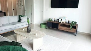 Un salon moderne avec un canapé, une table basse et un téléviseur fixé au mur.
