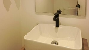 Une salle de bain avec un lavabo blanc, un miroir et une serviette accrochée au mur.