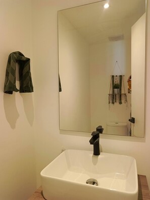 A bathroom with a white sink, a mirror, and a towel hanging on the wall. - Spacious 1-Bedroom Apartment with Shared Pool in Punta Cana (Punta Cana)