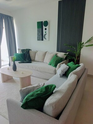 A modern living room with a sectional sofa, a round coffee table, and a potted plant. - Spacious 1-Bedroom Apartment with Shared Pool in Punta Cana (Punta Cana)