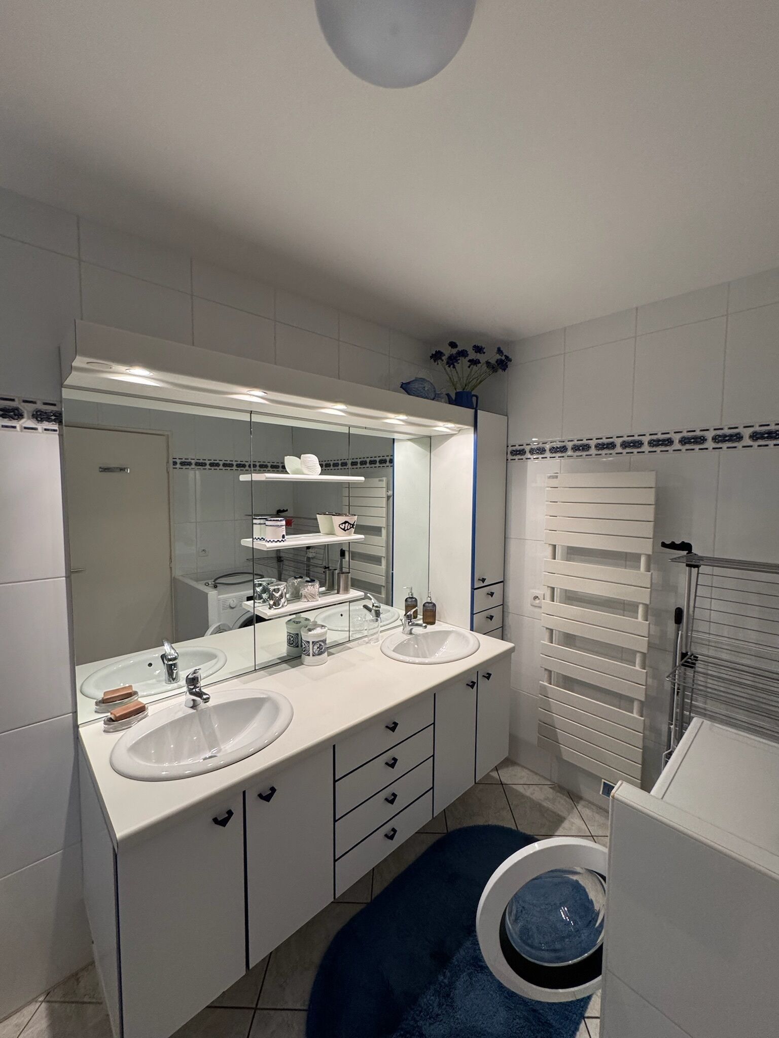 Ein modernes Badezimmer mit zwei Waschbecken, einem großen Spiegel und einem Handtuchhalter.