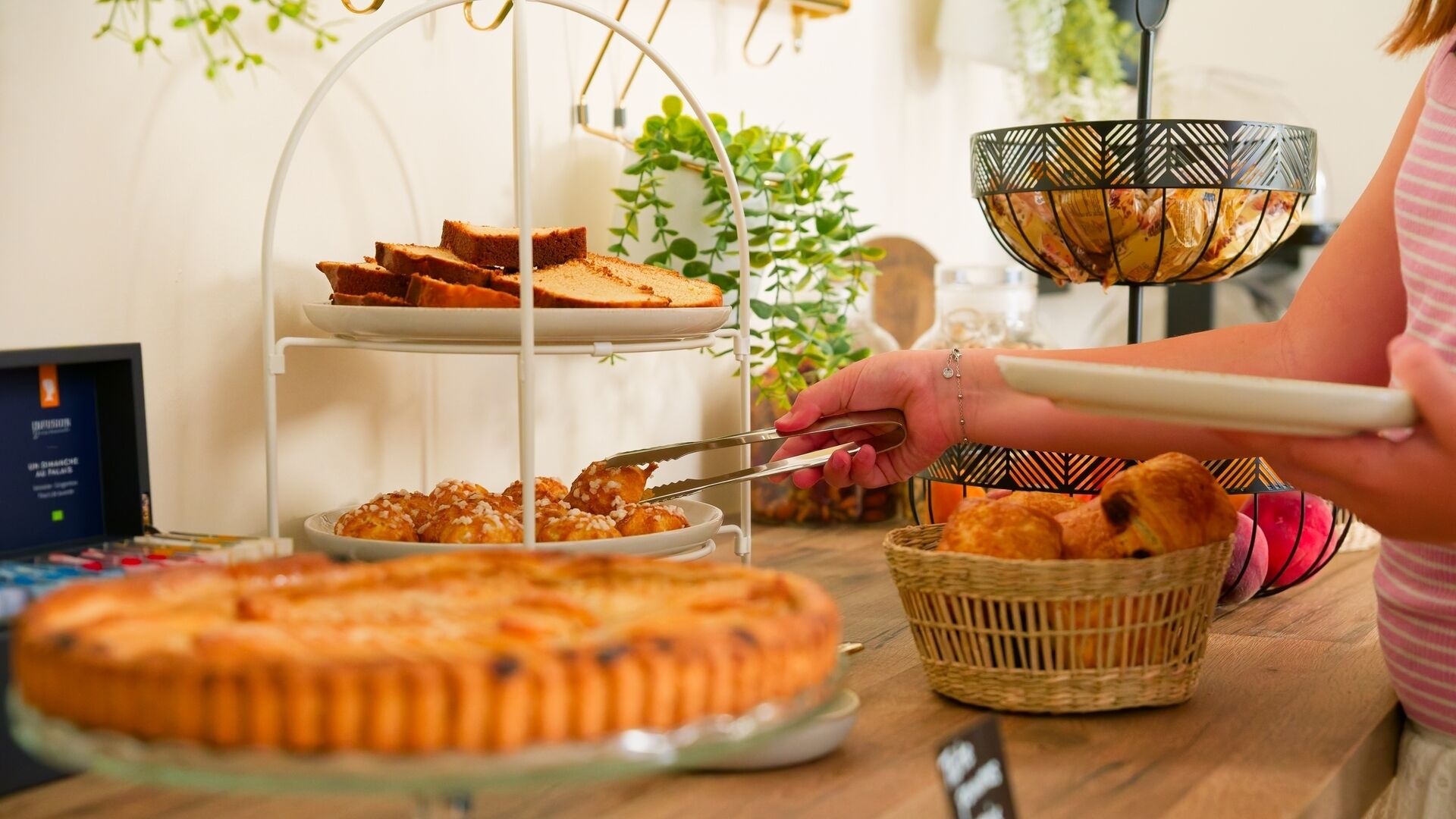 Tarjolla on runsas buffet, jossa on monenlaista ruokaa, kuten suuri pyöreä kakku, leipää ja kori pieniä sämpylöitä.