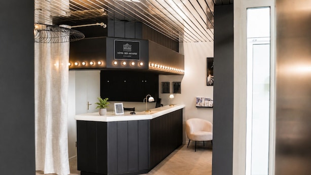 A reception area with a black counter, a potted plant, and a framed picture.