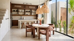 A modern kitchen with a central island, wooden chairs, and pendant lighting. - Modern 2BR Private Pool Villa Near Pererenan Beach & Canggu (Badung)
