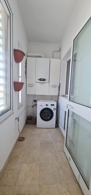 Une buanderie équipée d’un lave-linge à chargement frontal, d’un sèche-linge et d’une petite fenêtre.