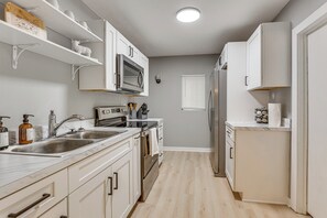 A modern kitchen with white cabinets, stainless steel appliances, and a marble countertop. - Walk to University of Akron! Game Day Getaway (Akron)