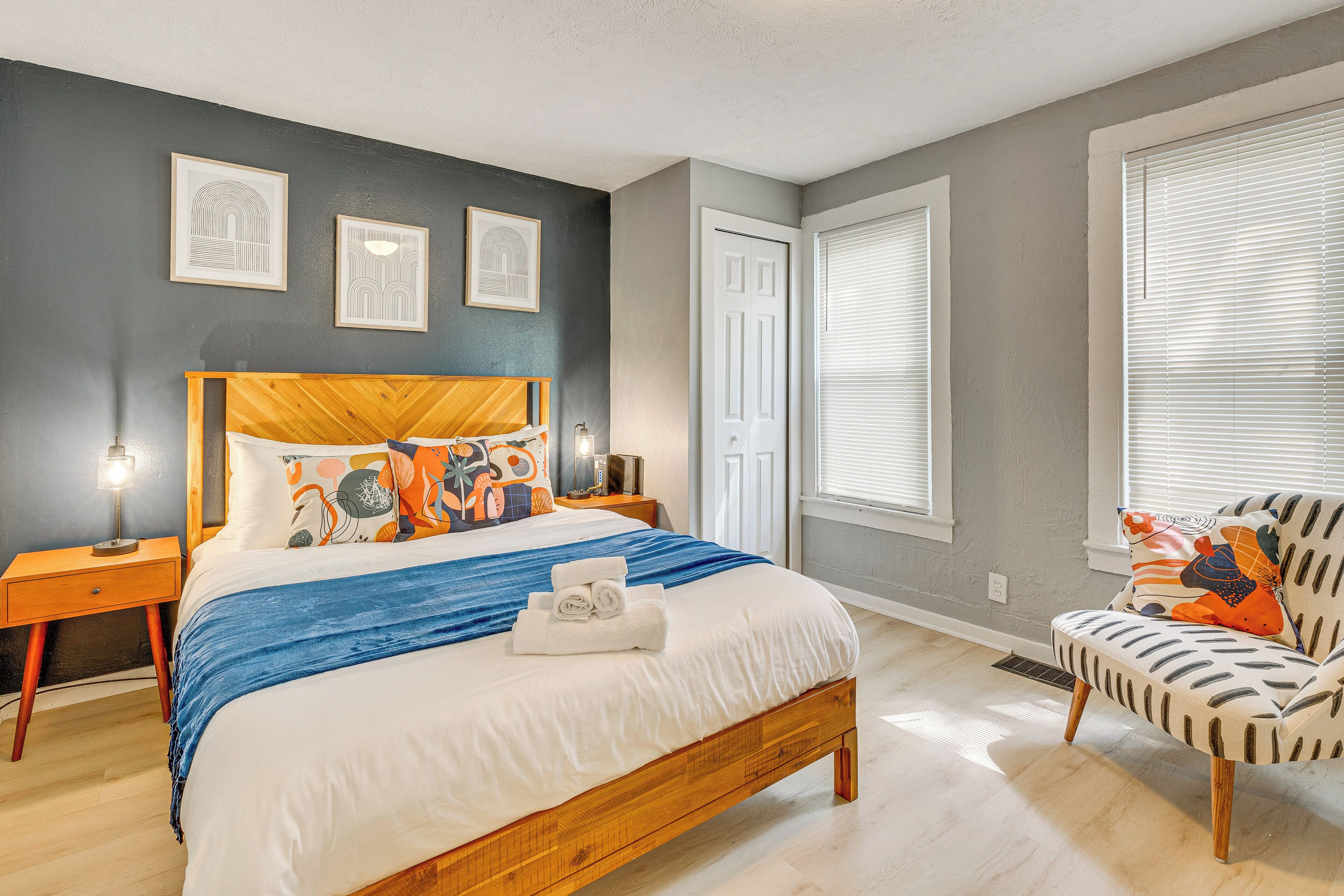 Une chambre à coucher avec un lit en bois, une table de chevet, une chaise et une fenêtre avec des stores.