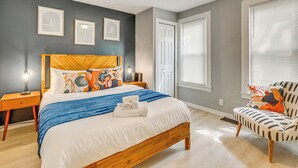 Quarto com cama de madeira, mesa de cabeceira, uma cadeira e janela com persianas.
