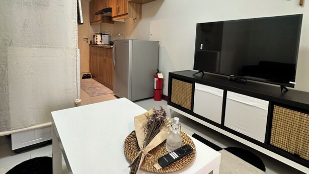 A compact living space with a kitchenette, a dining area, and a TV. - Nordic Nest Makati (Makati City)