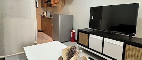 A compact living space with a kitchenette, a dining area, and a TV.