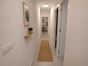 Ein Flur mit einem Holzbodenregal, einem gerahmten Bild und einem Teppich, der zu einem Zimmer führt.