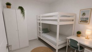 A bunk bed with a desk and chair, a small rug, a cabinet, and a plant on the wall. - Salinas Home (Antigua)